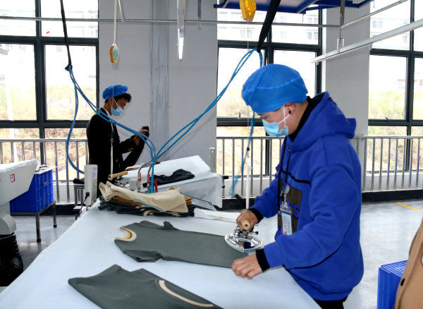 2022年4月1日,晶煌制衣有限公司生产车间工人在熨烫衣服.