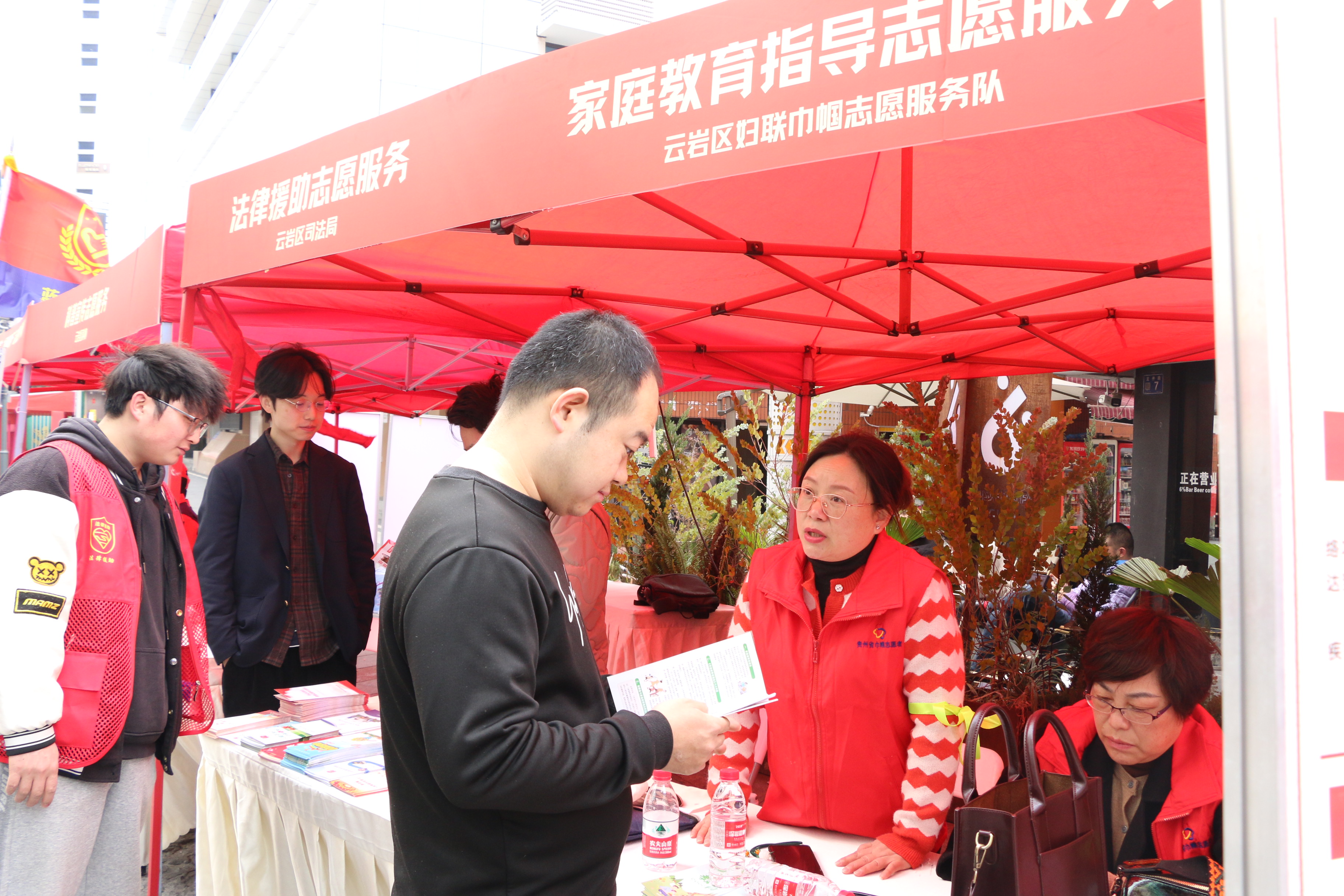 活动现场志愿服务展棚旁,志愿者正在给市民讲解家庭教育指导相关知识