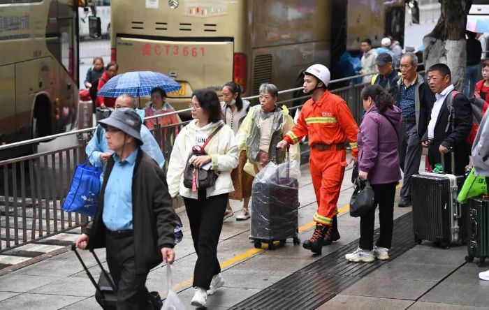 4月24日,在贵阳市南明区花果园,消防员正在为帮助游客搬运行李。2 图片