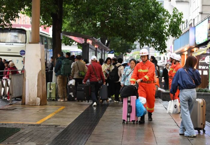 4月24日,在贵阳市南明区花果园,消防员正在为帮助游客搬运行李。 图片