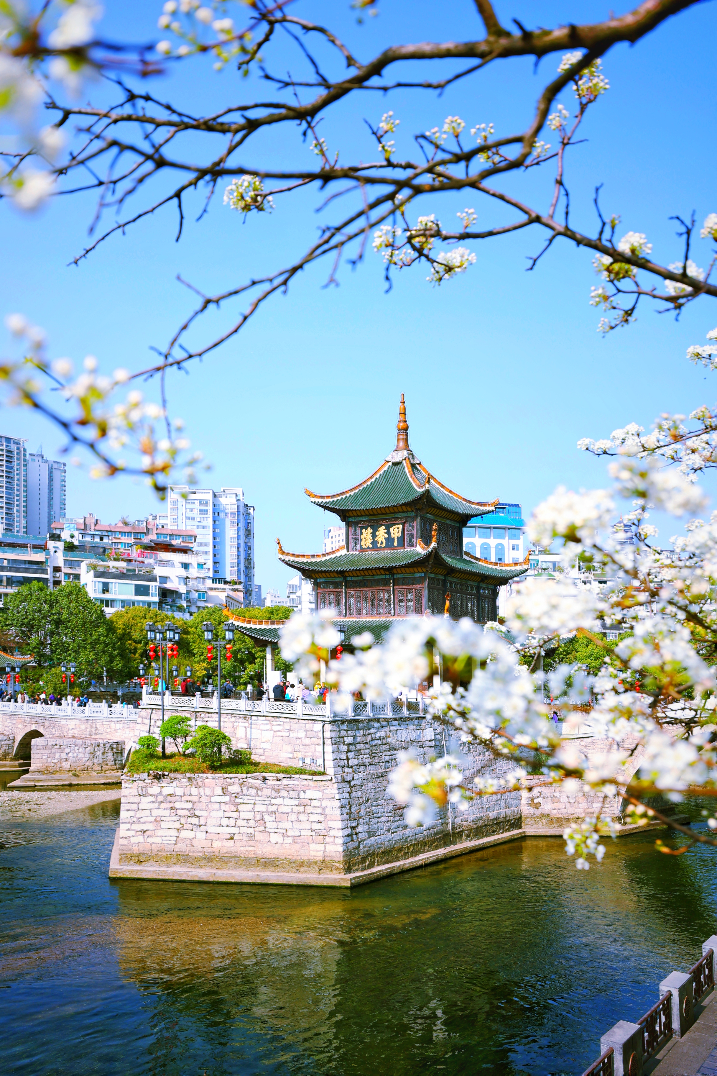 3月19日,游客在甲秀楼游玩赏景。 最近,有网友发现一处欣赏甲秀楼风光的全新角度:从位于箭道街一侧的南明河岸边茶馆看去,甲秀楼半掩于盛开的李花中,加之清澈见底的南明河水,洁白的岸边李花,悦耳的鸟鸣,空中自由飞翔的白鹭,使甲秀楼呈现出一种有别于常规视觉的魅力和美感来,令人更加赏心悦目,美不胜收,美妙的欣赏角度令不少游客纷纷前往打卡拍照。