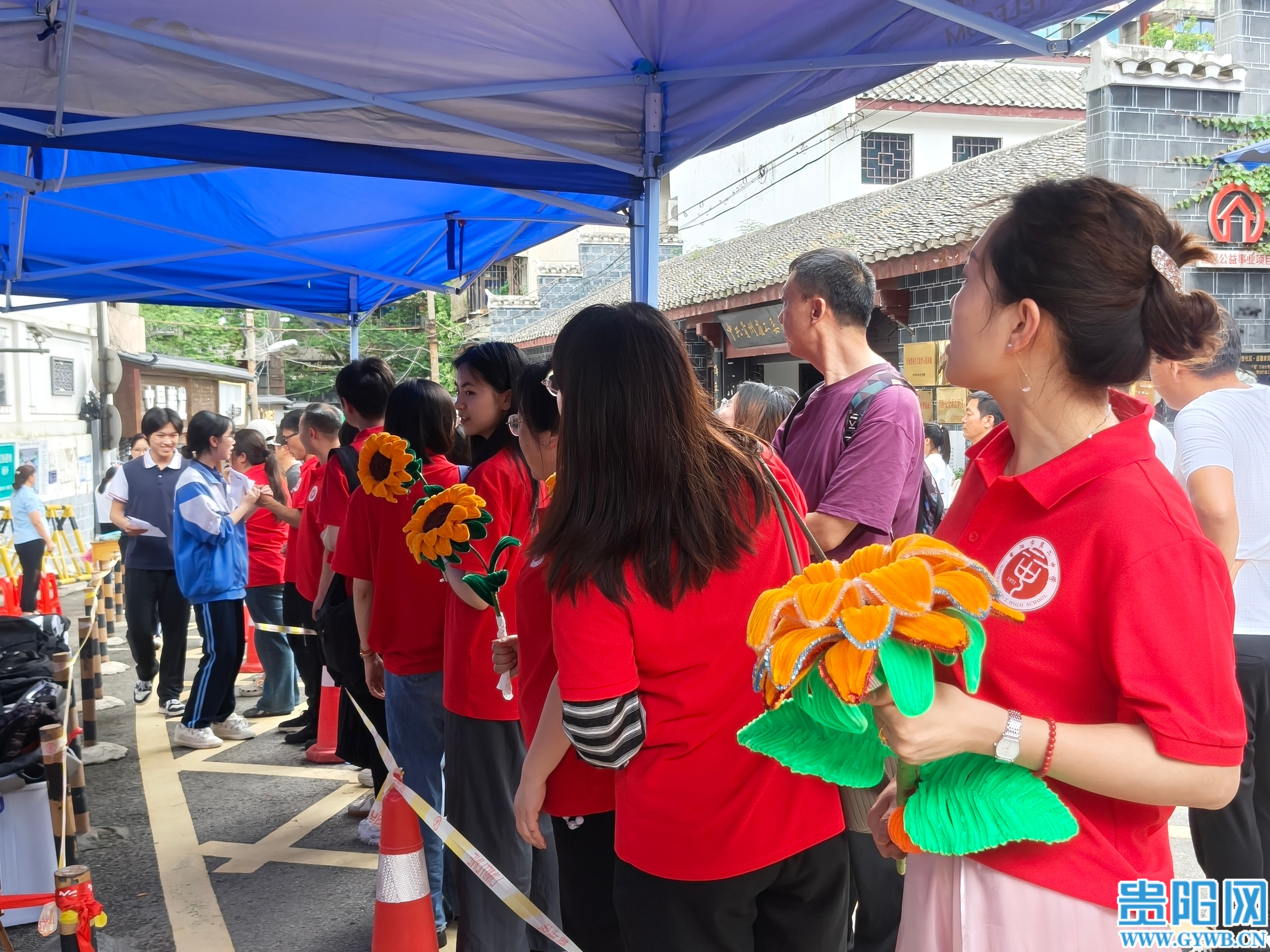2.黄老师与其他老师手持向日葵,在进校通道旁给同学们送上祝福 (1)
