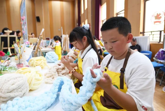 6月5日,贵阳市南明区兴关小学的学生正在劳动教育实践技能展演活动现场进行手指毛线纺织。 图片